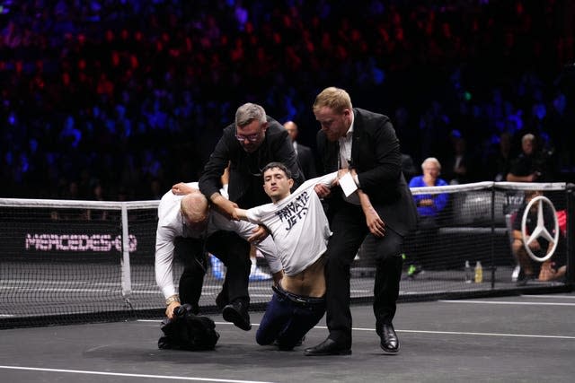 Stewards remove a protester who set fire to the court at the O2 Arena