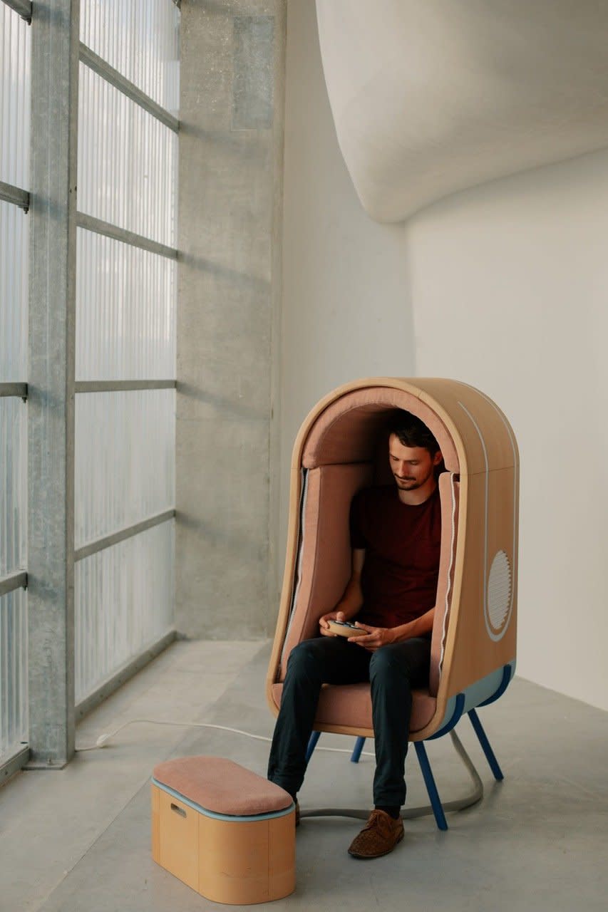 Man sits inside Audrain Alexia's OTO Chair and uses the built-in remote control to adjust pressure settings. 