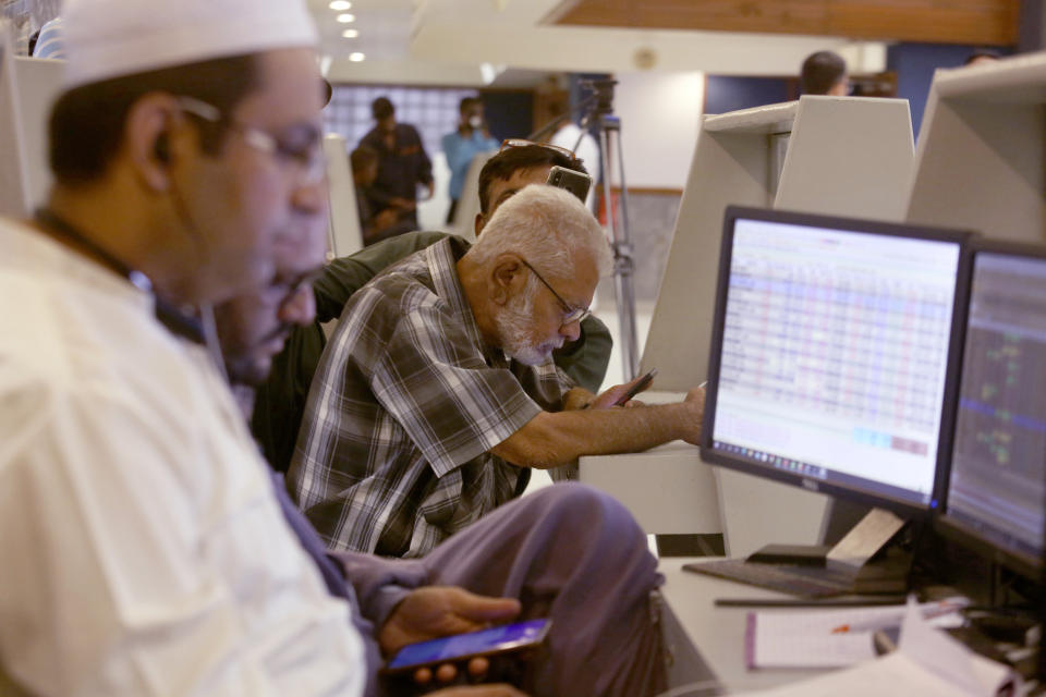 Pakistani brokers monitor Index on their mobile phones and monitor at at the Pakistan Stock Exchange (PSE), in Karachi, Pakistan, Friday, June 24, 2022. Pakistan's stock market suddenly fell by three percent on Friday, shortly after the government of recently elected Prime Minister Shahbaz Sharif suddenly announced the imposition of additional taxes on the corporate and banking sector in an effort aimed at stabilizing the country's fledgling economy. (AP Photo/Fareed Khan)