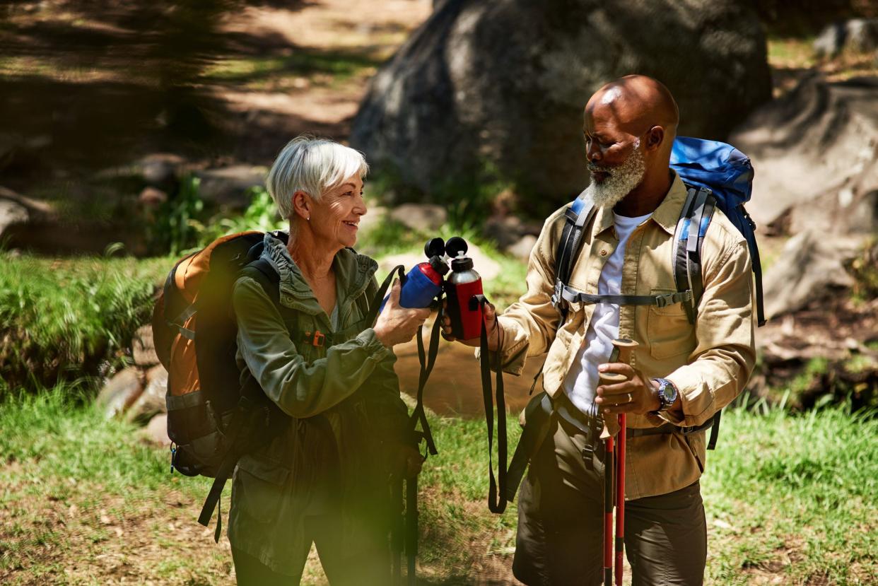 Shot of a senior couple holding water bottles while taking a break from their hike