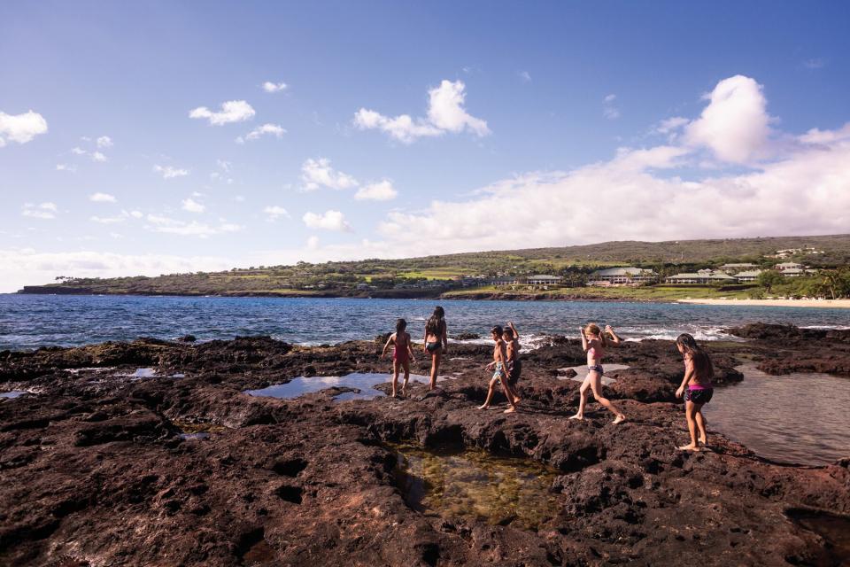 Children playing on rocks by the ocean at Four Seasons Lanai