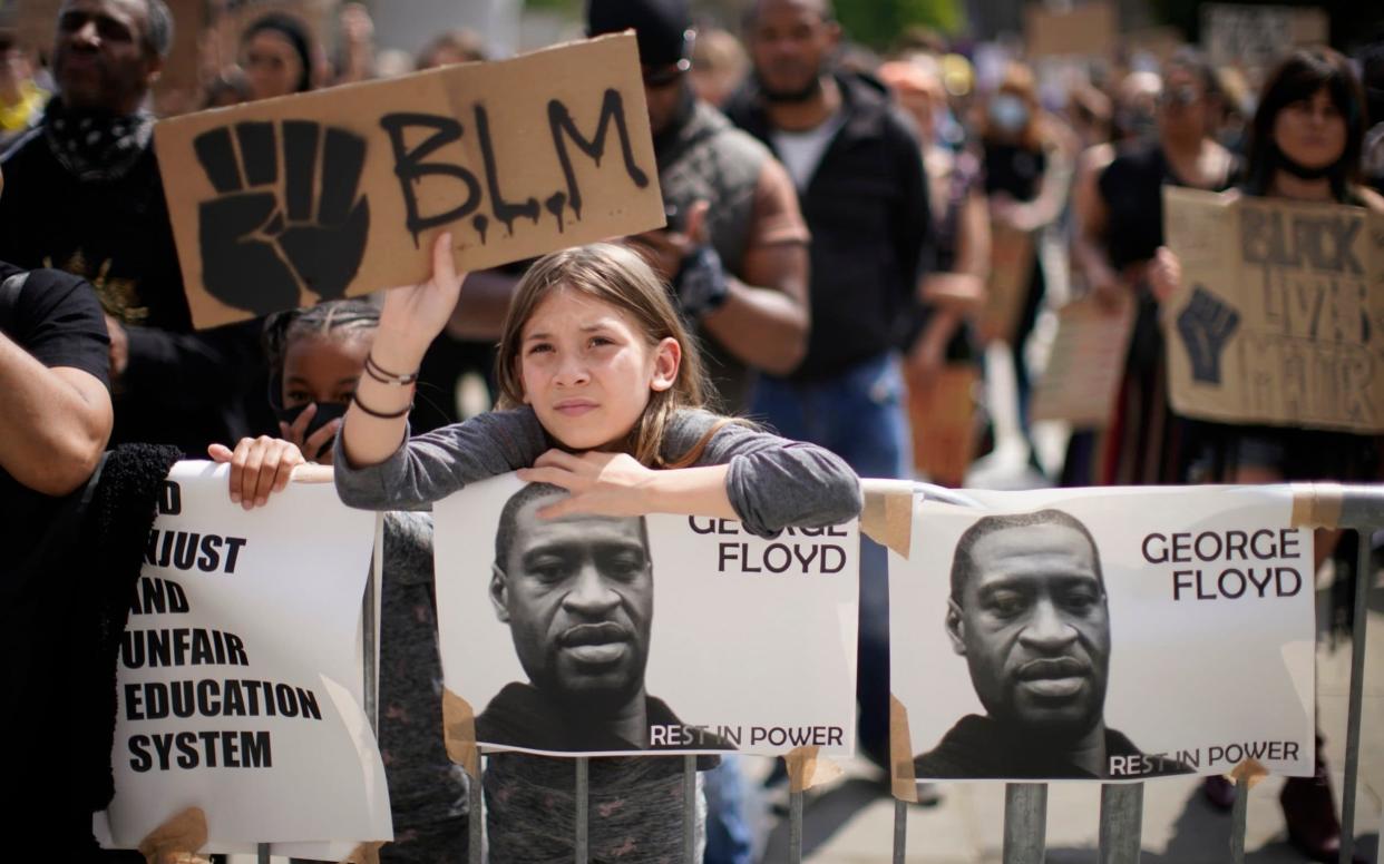 A young girl holds up a "BLM" sign during a Black Lives Matter rally in Millennium Square, Leeds on June 14 - Getty Images Europe 