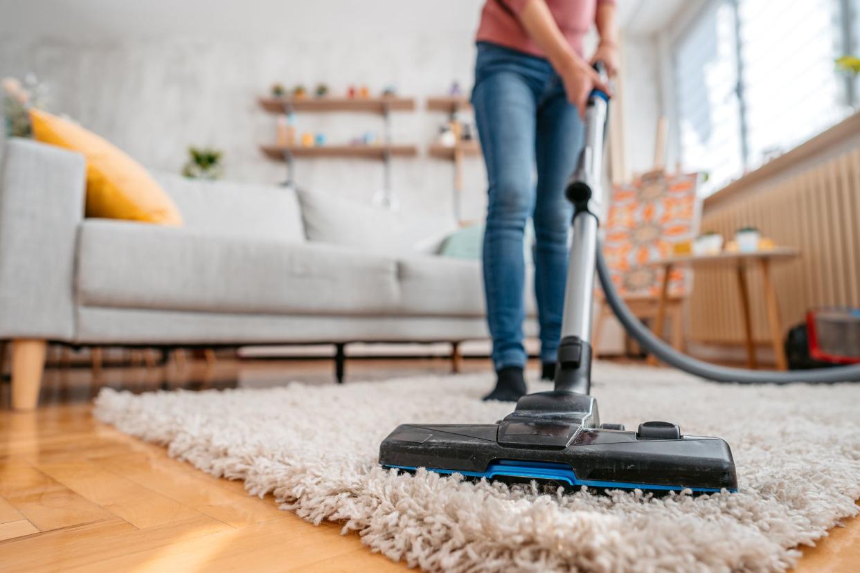 Beautiful young Asian woman vacuuming her apartment. Low angle view.