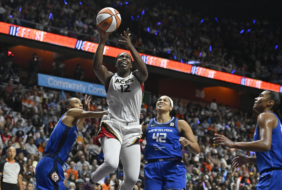 Las Vegas Aces' Chelsea Gray (12) goes up for a basket as Connecticut Sun's DeWanna Bonner, left, and Brionna Jones (42) defend during the second half in Game 4 of a WNBA basketball final playoff series, Sunday, Sept. 18, 2022, in Uncasville, Conn. (AP Photo/Jessica Hill)