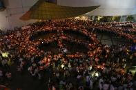 People hold candles as they form a peace sign during an anti-violence campaign in central Bangkok January 10, 2014. Thailand on Friday played down talk of a military coup ahead of a planned "shutdown" of the capital next week by protesters trying to overthrow Prime Minister Yingluck Shinawatra and said life would go on much as normal. REUTERS/Soe Zeya Tun (THAILAND - Tags: POLITICS CIVIL UNREST)