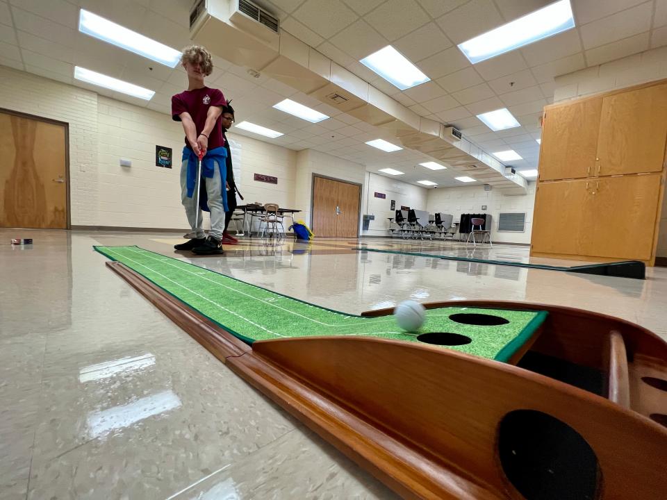 Cooper Weaver takes a practice putt in the cafeteria at Turning Point Academy.