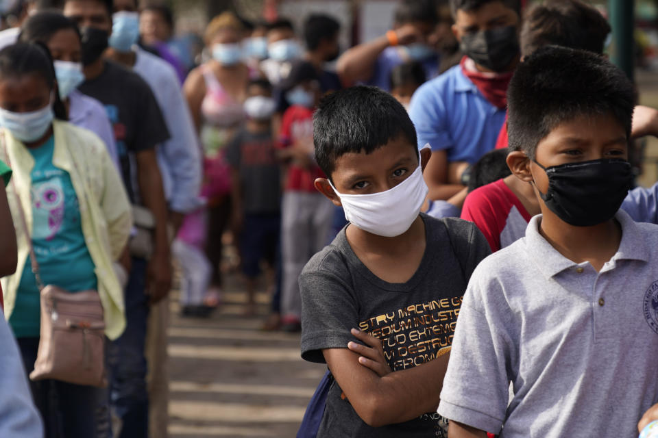 Children and adults wait in lines for donated food at a makeshift camp for migrants near the U.S.-Mexico border Friday, May 14, 2021, in Reynosa, Mexico. Growing numbers of migrant families are making the heart-wrenching decision to separate from their children and send them into the U.S. alone. (AP Photo/Gregory Bull)