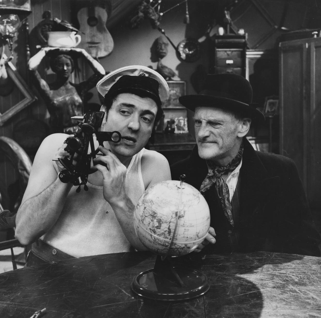 Actors Wilfrid Brambell (right) and Harry H Corbett sitting in front of a globe in a scene from episode 'Homes Fit for Heroes' of the television sitcom 'Steptoe and Son', December 12th 1963. (Photo by Don Smith/Radio Times/Getty Images)