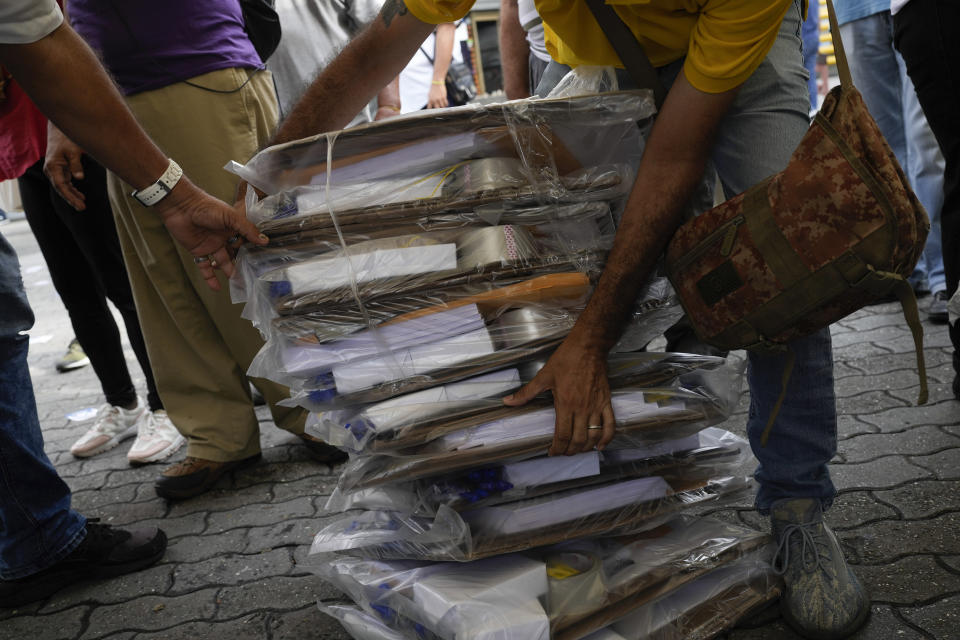 People bring voting tables to open a polling station during primary election at the Luis Brion square in Caracas, Venezuela, Sunday, Oct. 22, 2023. (AP Photo/Matias Delacroix)