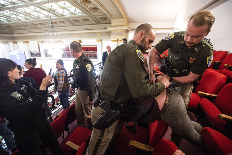 A demonstrator is arrested in the gallery of the House of Representatives during a protest after the Speaker of the House refused again to acknowledge Rep. Zooey Zephyr, D-Missoula, on Monday, April 24, 2023, in the State Capitol in Helena, Mont. Republican legislative leaders in Montana persisted in forbidding the Democratic transgender lawmaker from participating in debate for a second week as her supporters brought the House session to a halt Monday, chanting "Let her speak!" from the gallery before they were escorted out. (Thom Bridge/Independent Record via AP)