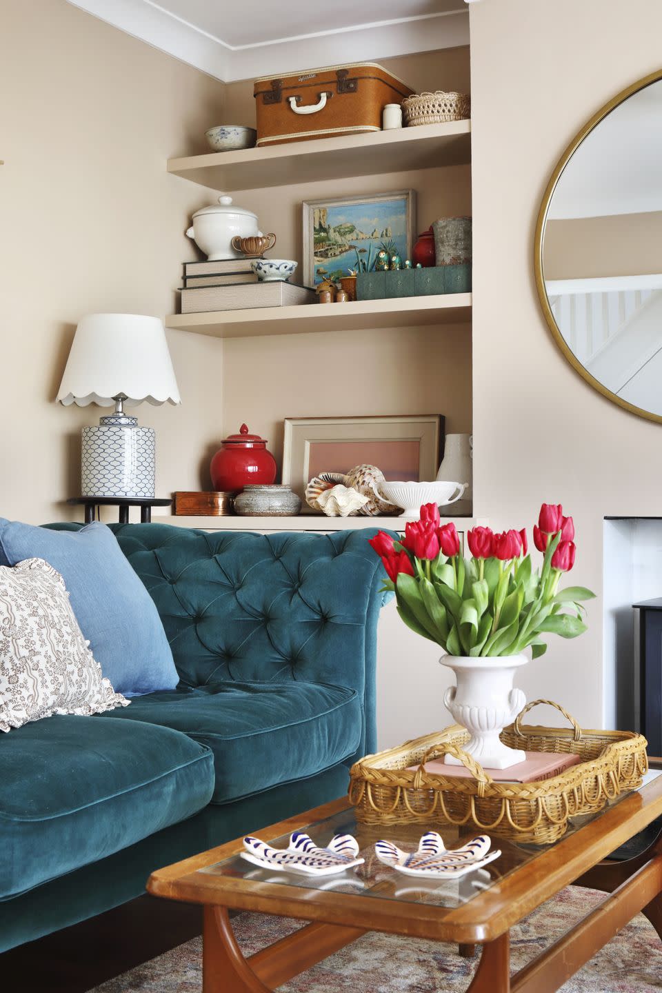 a soft pink living room with a blue sofa and built in alcove shelving showcasing art and trinkets