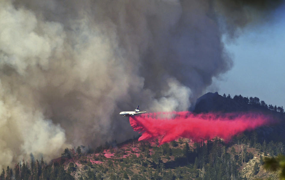 A plane drops fire retardant on the Washburn Fire as it burns near the Mariposa Grove of giant sequoias and the south entrance of Yosemite National Park, in California, Monday, July 11, 2022. (Eric Paul Zamora/The Fresno Bee via AP)