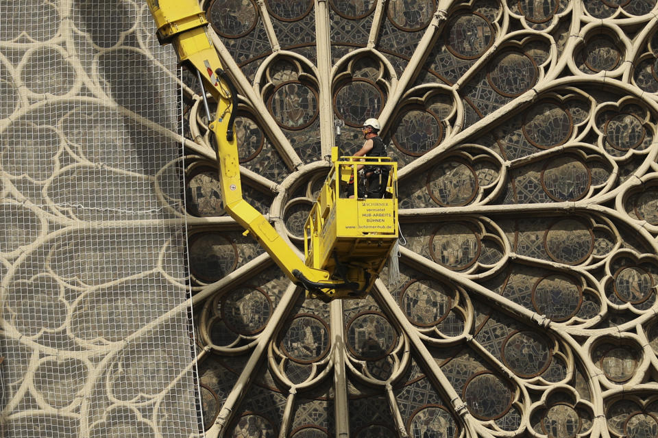 Workers fix a net to cover one of the iconic stained glass windows of the Notre Dame Cathedral in Paris, Sunday, April 21, 2019. The fire that engulfed Notre Dame during Holy Week forced worshippers to find other places to attend Easter services, and the Paris diocese invited them to join Sunday's Mass at the grandiose Saint-Eustache Church on the Right Bank of the Seine River. (AP Photo/Francisco Seco)