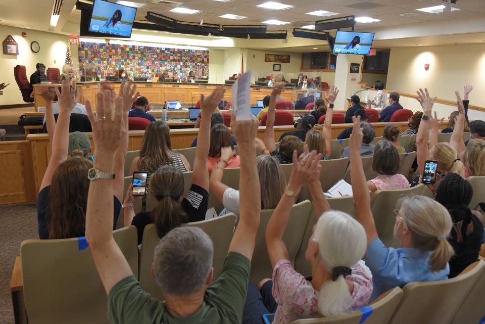 People concerned about Duval County school district mask policies raise their hands as Moms for Liberty member Tia Bess (right, at podium) talks to School Board members in August 2021.