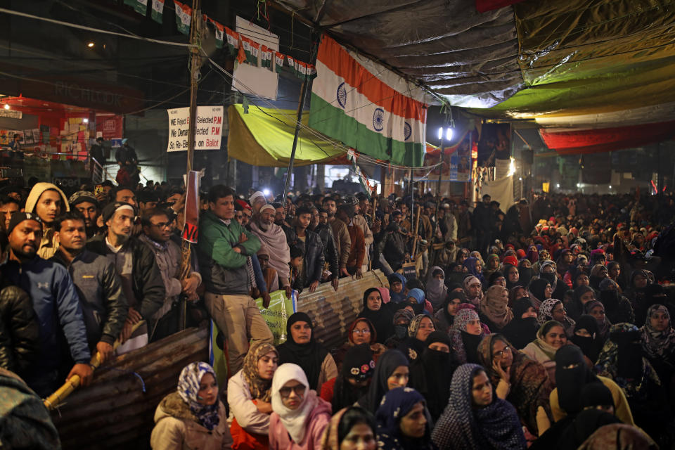 In this Tuesday, Jan. 21, 2020 photo, men stand outside while women protesters sit inside a tent as they listen to a speaker at the protest site in New Delhi's Shaheen Bagh area, India. The gathering at Shaheen Bagh started with a handful of women appalled by the violence at a nearby Muslim university during protests against the law on Dec. 15. Since then it has slowly morphed into a nationwide movement, with many women across the country staging their own sit-ins. They sing songs of protest and chant anti-government slogans, some cradling babies, others laying down rugs to make space for more people to sit. (AP Photo/Altaf Qadri)