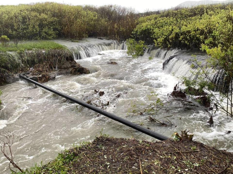Water rushes under an exposed gas main in Old Creek near Studio Drive in Cayucos on Tuesday, March 14, 2023.