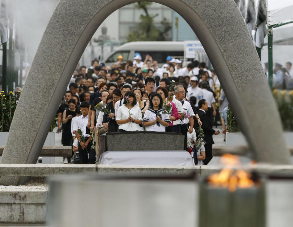 People pray for the atomic bomb victims in front of the cenotaph at the Hiroshima Peace Memorial Park in Hiroshima, western Japan during a ceremony to mark the 74th anniversary of the bombing Tuesday, Aug. 6, 2019. (Kyodo News via AP)