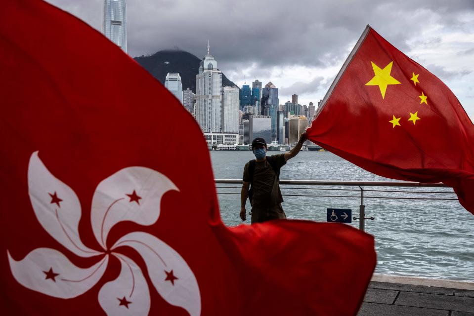 TOPSHOT - A man waves the Chinese flag to celebrate the 25th anniversary of the city's handover from Britain to China, in Hong Kong on July 1, 2022. (Photo by ISAAC LAWRENCE / AFP) (Photo by ISAAC LAWRENCE/AFP via Getty Images)