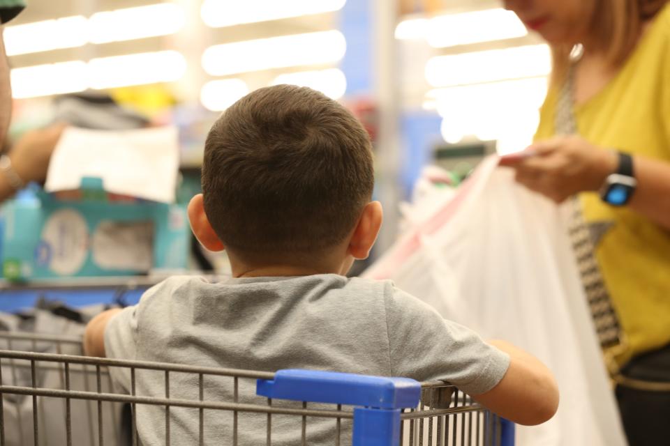 A Sinton Elementary students waits in a shopping cart as his new clothes and toys are placed in a bag by Sinton for Youth board member Elizabeth Fagin at the Walmart in Portland on Saturday, Dec. 10, 2022. The elementary student was able to purchase clothes and toys courtesy of the nonprofit Sinton for Youth.