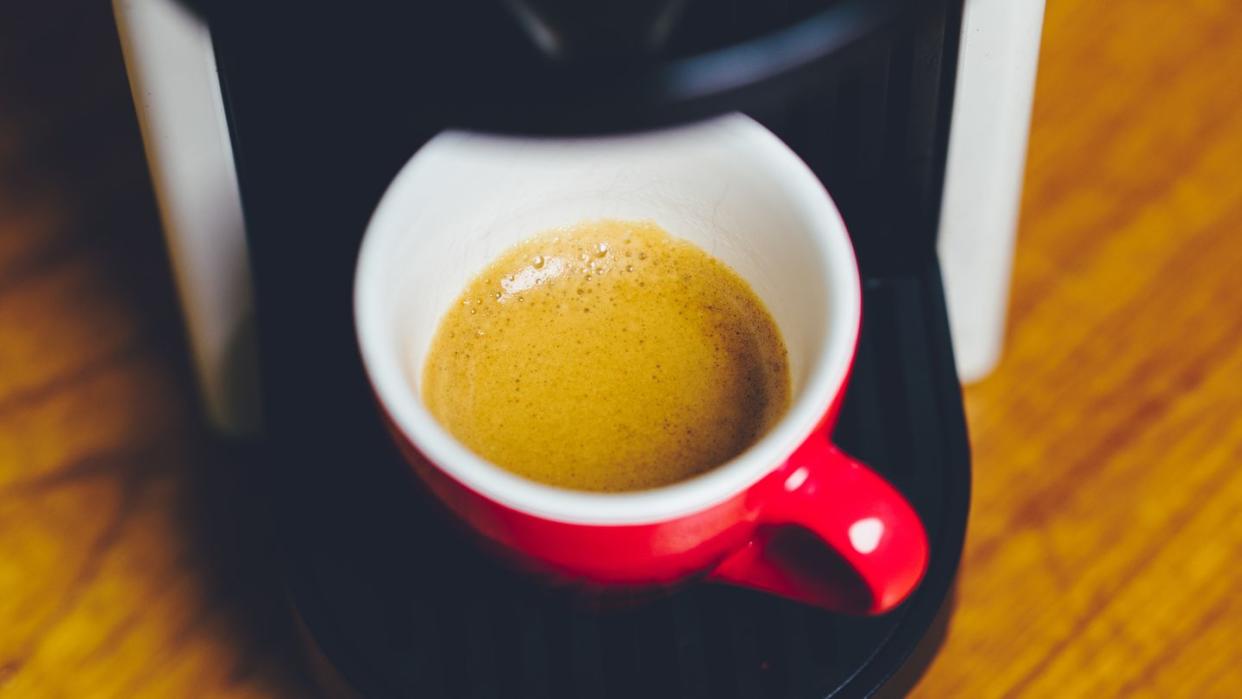 close up of a red coffee espresso cup on a nespresso machine in moody setting