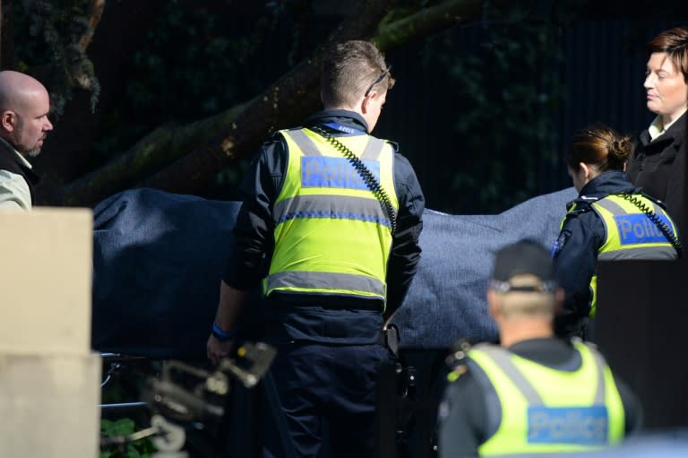 Police officers help the coroner remove a body from the scene of a hostage situation in the Melbourne bayside suburb of Brighton on June 6, 2017