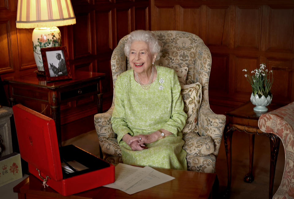 In pale green dress and seated in a wing armchair near lamps and flowers, a smiling Queen Elizabeth II is photographed at Sandringham House to mark the start of Her Majesty’s Platinum Jubilee Year, on February 2, 2022 in Sandringham, Norfolk.