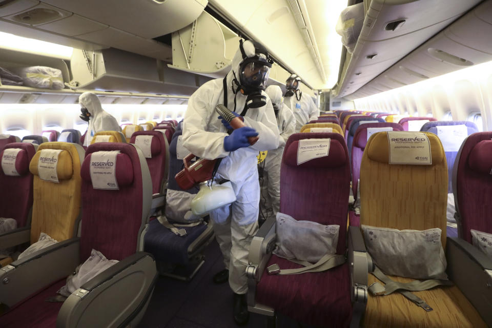 Crew members in protective suits and masks spraying during the disinfection process.