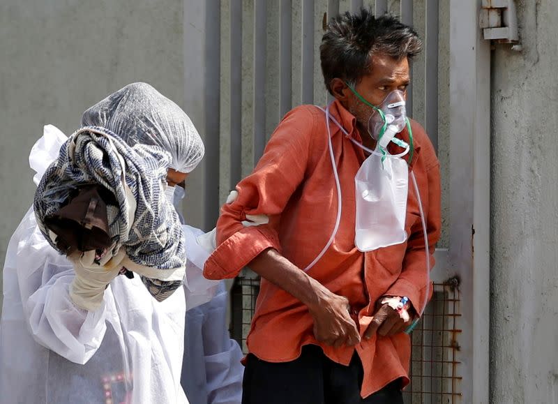 A patient with breathing problem is helped to walk towards an ambulance amidst the spread of the coronavirus disease (COVID-19) in Ahmedabad