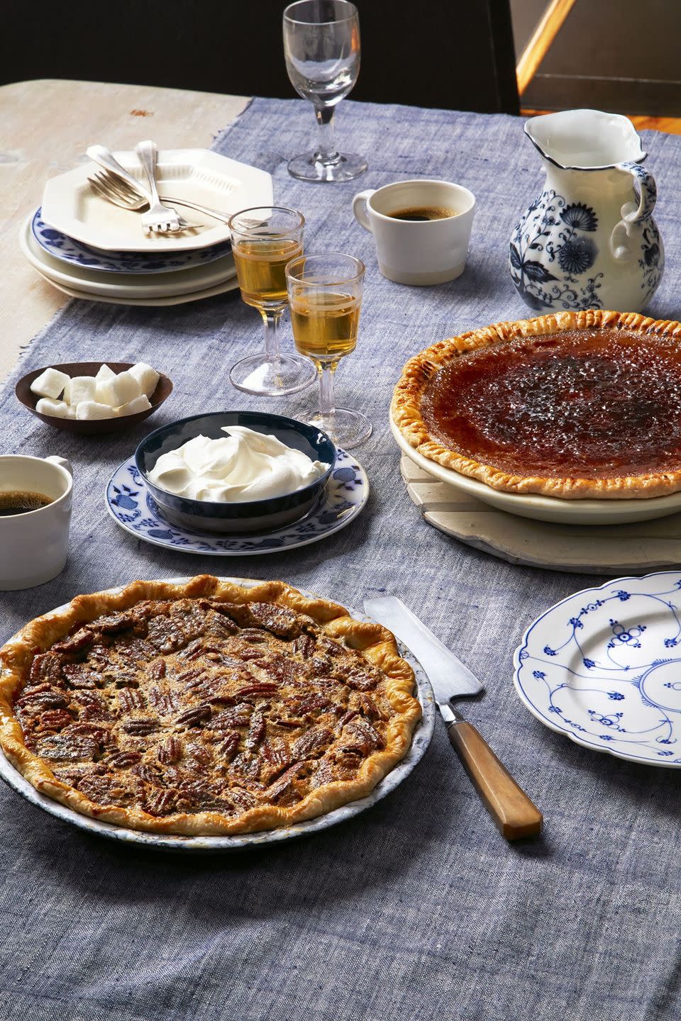 boozy pecan pie with a pie server and a bowl of whipped cream for serving