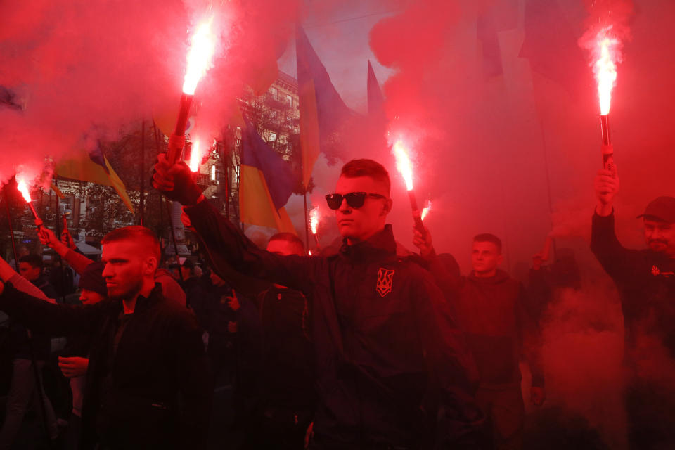 Members of the nationalist movements light flares during a rally marking Defense of the Homeland Day in center Kyiv, Ukraine, Monday, Oct. 14, 2019. Some 15,000 far-right and nationalist activists protested in the Ukrainian capital, chanting "Glory to Ukraine" and waving yellow and blue flags. President Volodymyr Zelenskiy urged participants to avoid violence and warned of potential “provocations” from those who want to stoke chaos. (AP Photo/Efrem Lukatsky)