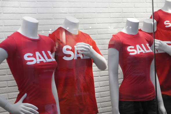 Mannequins behind glass with a sale sign on their red T-shirts, store sale in a shopping mall on a Boxing Day in Toronto, Canada