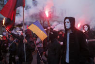 Members of the nationalist movements light flares during a rally marking Defense of the Homeland Day in center Kyiv, Ukraine, Monday, Oct. 14, 2019. Some 15,000 far-right and nationalist activists protested in the Ukrainian capital, chanting "Glory to Ukraine" and waving yellow and blue flags. President Volodymyr Zelenskiy urged participants to avoid violence and warned of potential “provocations” from those who want to stoke chaos. (AP Photo/Efrem Lukatsky)