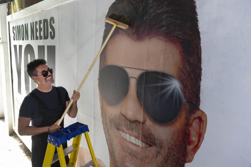 Simon Cowell putting up poster