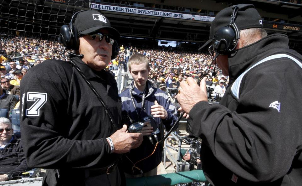 First base umpire Bob Davidson, right, and home plate umpire John Hirschbeck, left, talk over headsets as a play at first base is being reviewed in the fifth inning during the opening day baseball game between the Pittsburgh Pirates and the Chicago Cubs on Monday, March 31, 2014, in Pittsburgh. Chicago Cubs manager Rick Renteria requested a replay on an out call. (AP Photo/Gene Puskar)