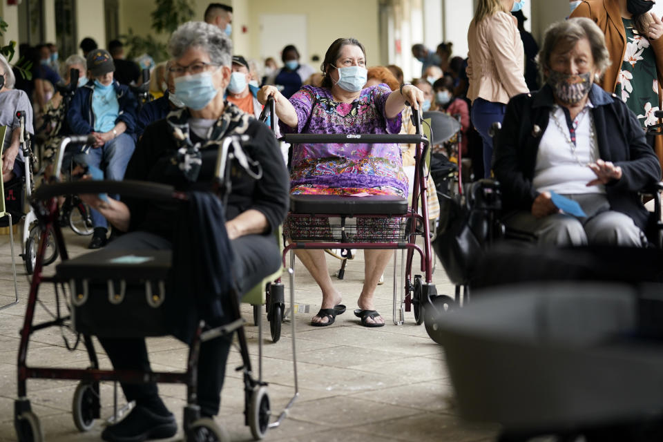 FILE - In this Tuesday, Jan. 12, 2021 photo, Resident Sabeth Ramirez, 80, center, waits in line with others for the Pfizer-BioNTech COVID-19 vaccine at the The Palace assisted living facility in Coral Gables, Fla. Florida was one of the first states to throw open vaccine eligibility to members of the general public over 65, leading to rumors that tourists and day-trippers are swooping into the state solely for the jab. Gov. Ron DeSantis said stories of the rich flying to Florida, getting vaccinated and returning home are overblown. (AP Photo/Lynne Sladky, File)