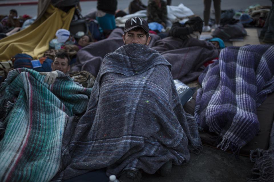 A migrant sits wrapped in a blanket at the Chaparral border crossing in Tijuana, Mexico, Friday early morning, Nov. 23, 2018. The mayor of Tijuana has declared a humanitarian crisis in his border city and says that he has asked the United Nations for aid to deal with the approximately 5,000 Central American migrants who have arrived in the city. (AP Photo/Rodrigo Abd)