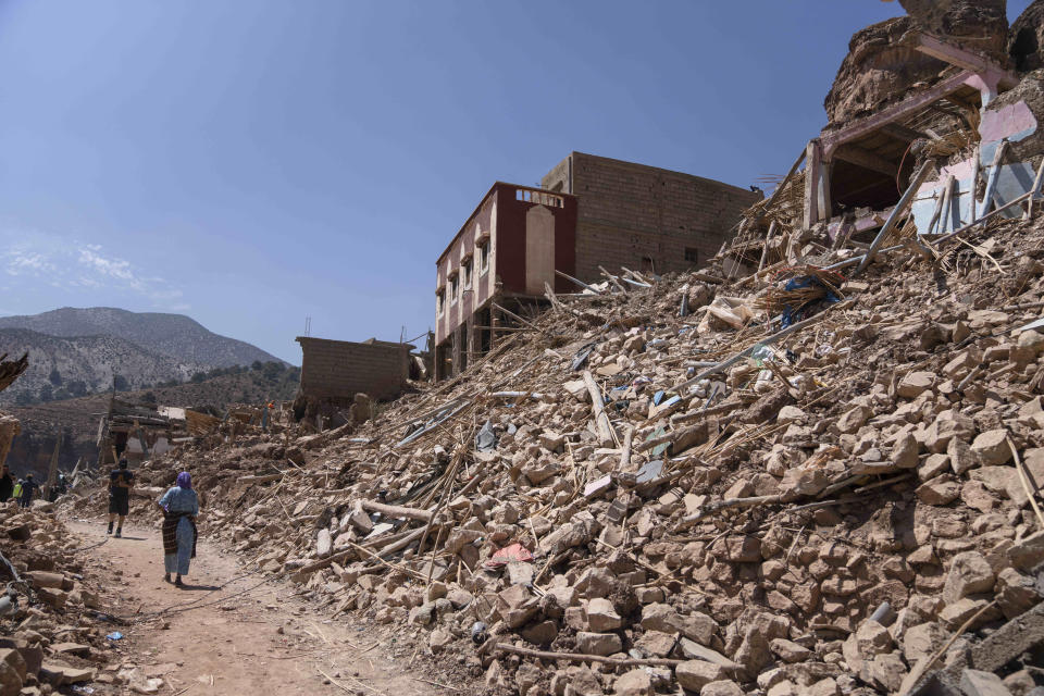 People walk amid the wreckage which was caused the earthquake, in the town of Imi N'tala, outside Marrakech, Morocco, Tuesday, Sept. 12, 2023. (AP Photo/Mosa'ab Elshamy)