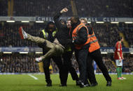 A football fan is carried off the pitch by security personnel after running on the field as Chelsea take on Swansea City during their English League Cup semi-final soccer match at Stamford Bridge in London January 9, 2013. REUTERS/Dylan Martinez (BRITAIN - Tags: SPORT SOCCER TPX IMAGES OF THE DAY CAPITAL ONE CUP)