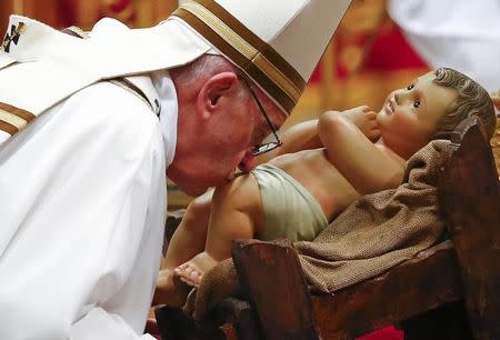 Pope Francis kisses a statue of baby Jesus at the end of the Christmas night Mass in Saint Peter's Basilica at the Vatican December 24, 2016. REUTERS/Tony Gentile