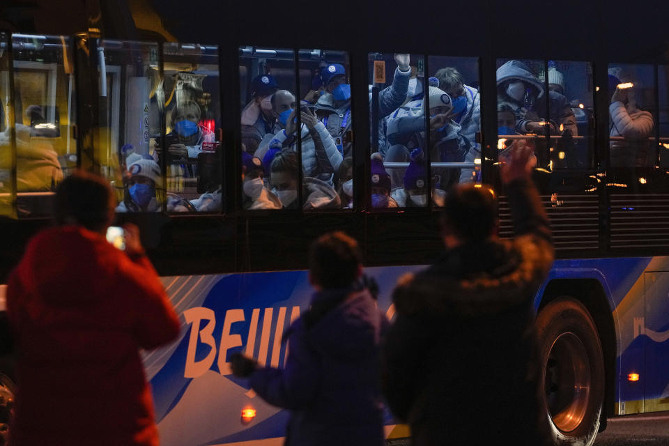 FILE - Foreign athletes inside a bus respond to residents on a street as they were heading to the National Stadium ahead of the opening ceremony of the 2022 Winter Olympics, in Beijing, Friday, Feb. 4, 2022. (AP Photo/Andy Wong, FIle)