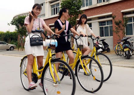 Students pose for pictures as they use ofo sharing bicycles at a campus in Zhengzhou, Henan province, China, September 6, 2016. China Daily/via REUTERS/File Photo