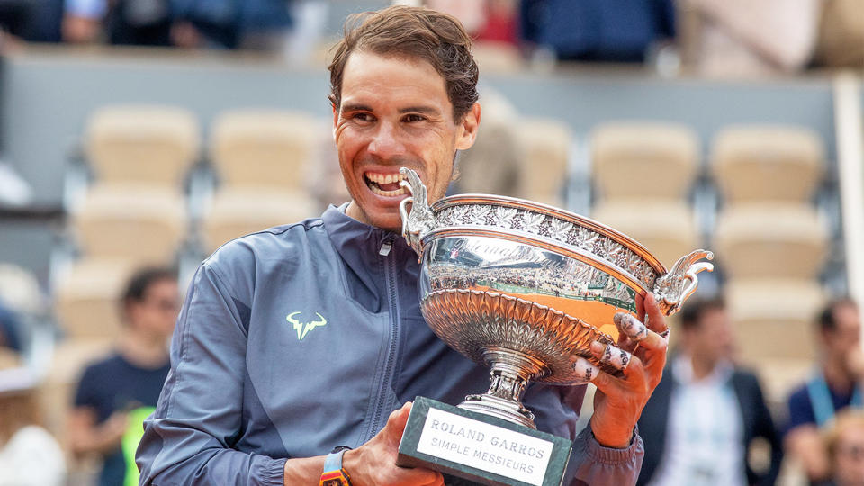 Rafael Nadal biting the French Open trophy in celebration.