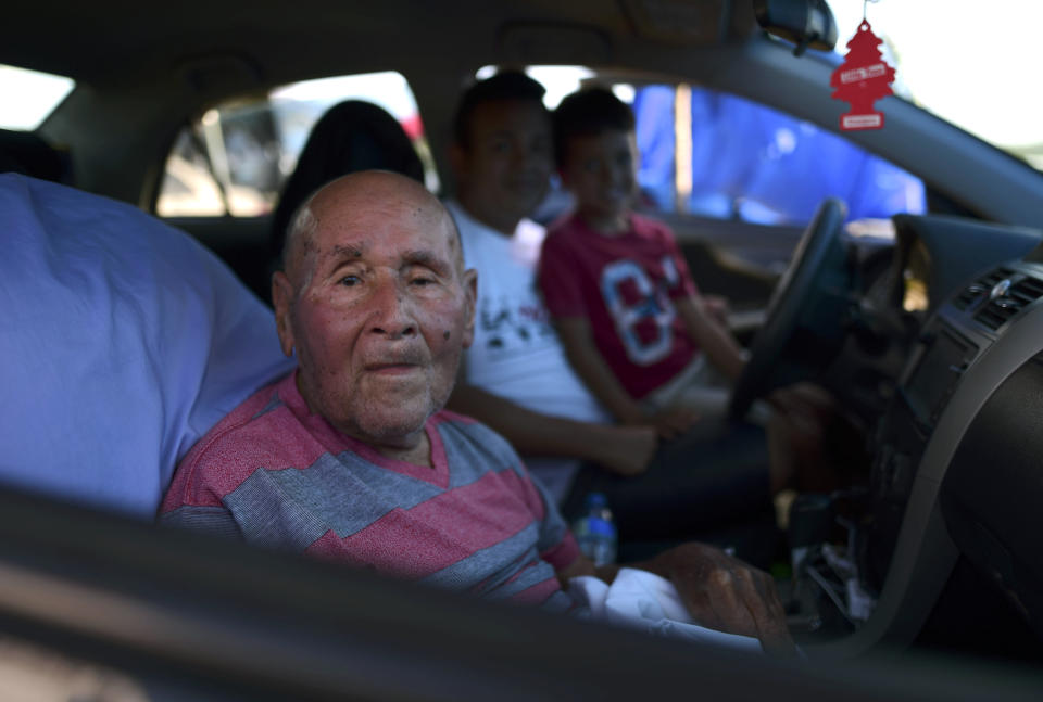 In this Friday, Jan. 10 photo, 83-year-old Angel Luis Pacheco sits with family inside a car parked on a hay farm where residents from the Indios neighborhood of Guayanilla, Puerto Rico, have set up shelter after earthquakes and amid aftershocks in Guayanilla, Puerto Rico. A 6.4 magnitude quake that toppled or damaged hundreds of homes in southwestern Puerto Rico is raising concerns about where displaced families will live, while the island still struggles to rebuild from Hurricane Maria two years ago. (AP Photo/Carlos Giusti)