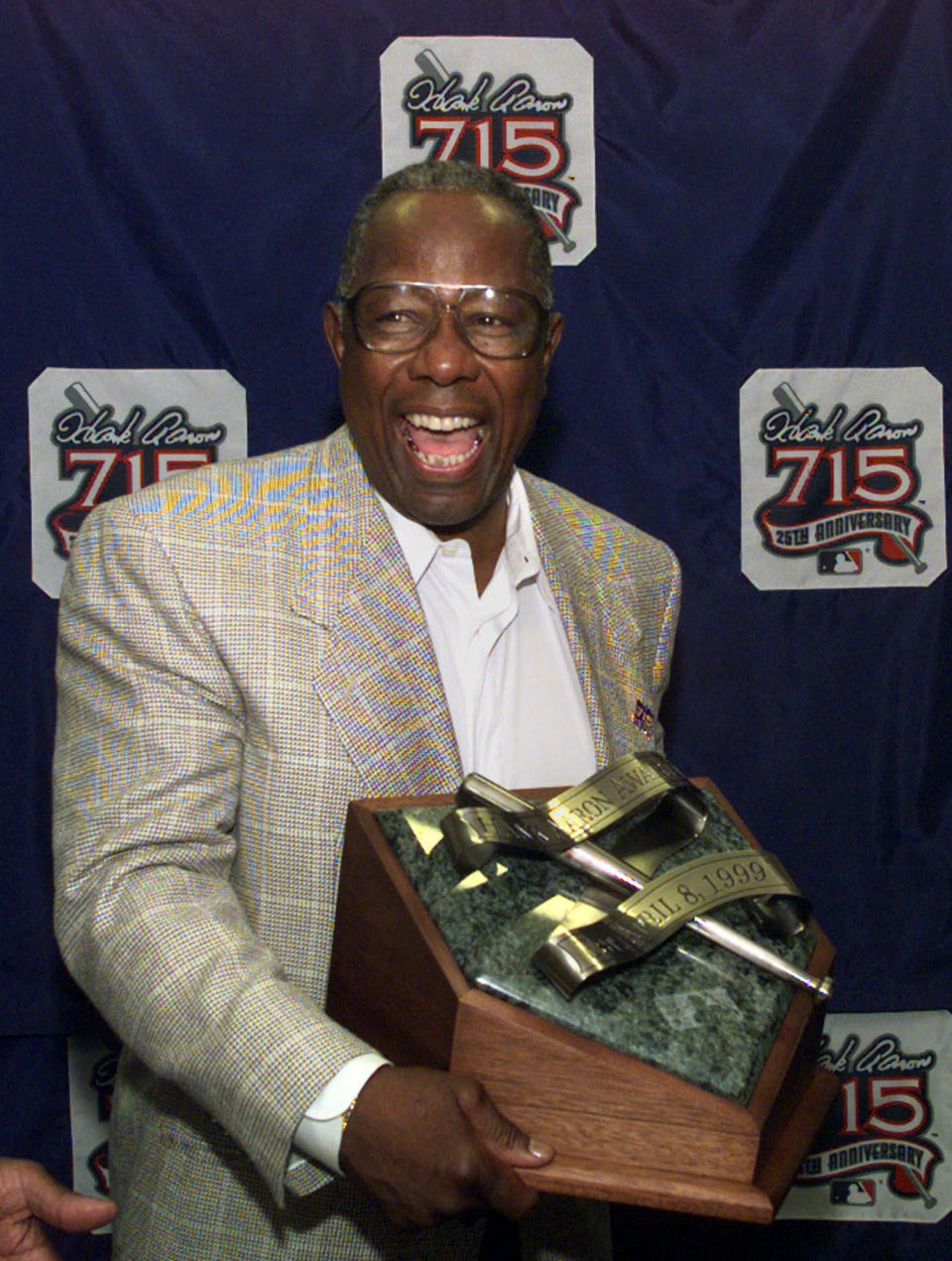 FILE - In this April 8, 1999, file photo, Major League Baseball's all-time career home run record holder Hank Aaron laughs as he shows off the newly unveiled "Hank Aaron Award" during a news conference in Atlanta. Hank Aaron, who endured racist threats with stoic dignity during his pursuit of Babe Ruth’s home run record and gracefully left his mark as one of baseball’s greatest all-around players, died Friday. He was 86. The Atlanta Braves, Aaron's longtime team, said he died peacefully in his sleep. No cause was given. (AP Photo/John Bazemore, File)