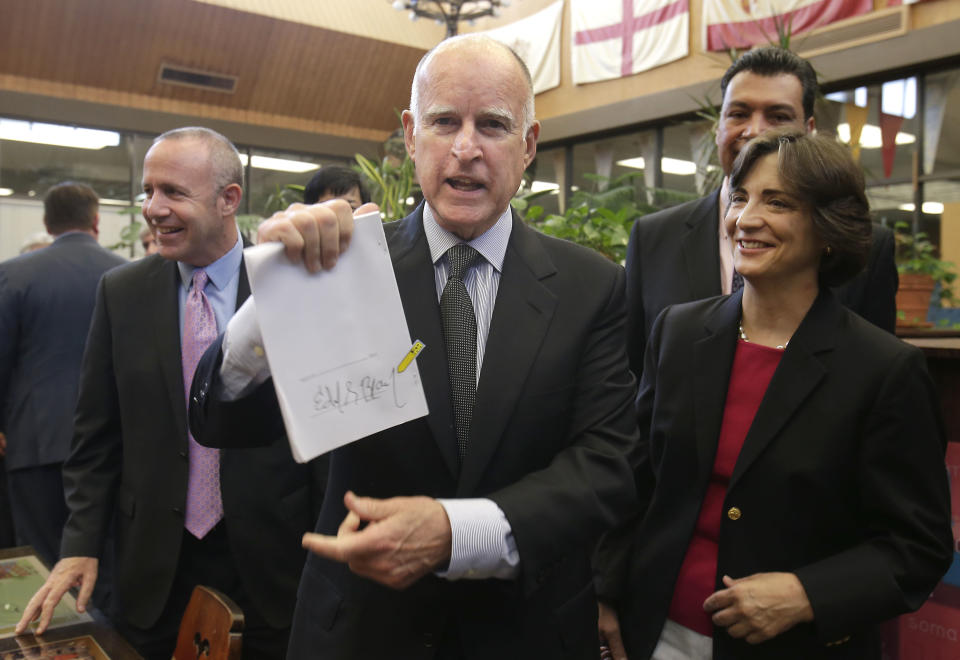 FILE - In this July 1, 2013 file photo, Gov. Jerry Brown holds up a copy of the education bill he signed during a ceremonial signing held at California Middle School in Sacramento, Calif. In his second stint as California's chief executive, Brown has received wide praise for bringing the state's massive budget deficit into line and enters the final year of his third term with a 58 percent approval rating.(AP Photo/Rich Pedroncelli, File)