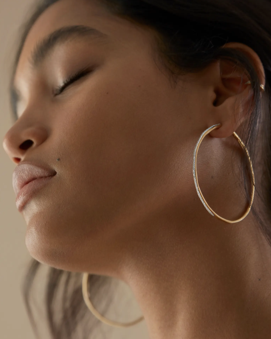 model with closed eyes wearing gold and diamond Monica Vinader Riva Cocktail Diamond Hoop Earrings (Photo via Nordstrom)