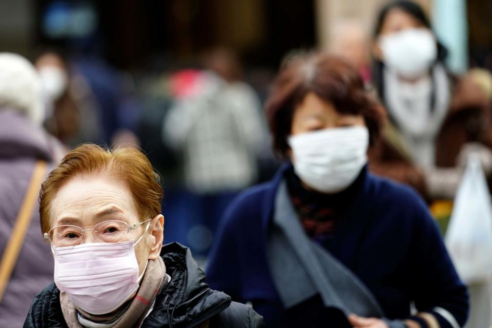 Pedestrians wear protective masks as they walk through a shopping district in Tokyo: AP