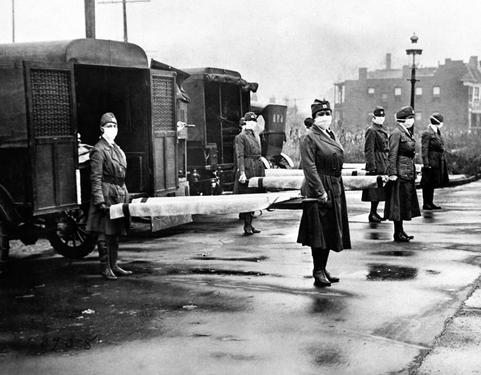 The St Louis Red Cross Motor Corps on duty with mask-wearing women holding stretchers at the backs of ambulances during the Influenza epidemic, St Louis, Missouri, October 1918. (Photo by Underwood Archives/Getty Images)