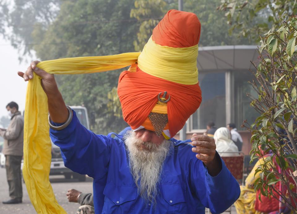 A ‘Nihang’ or Sikh religious warrior ties his turban during the ongoing farmers’ agitation over the new farm laws, in New Delhi, on Sunday, 17 January 2021.