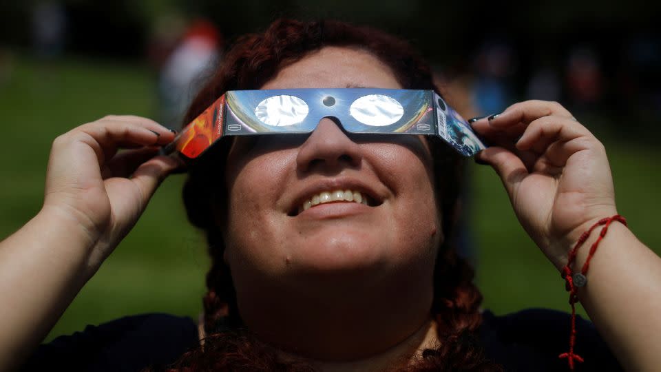 A woman uses eclipse glasses to observe an annular solar eclipse in Bicentenario Park in Antiguo Cuscatlan, El Salvador, on October 14, 2023. - Jose Cabezas/Reuters